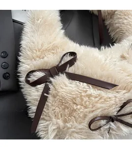 Close-up of plush faux fur underarm bag with decorative dark brown leather bow