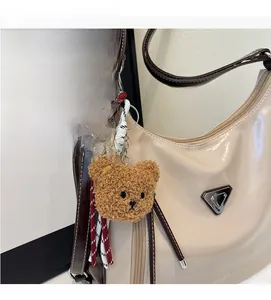 Detail eines braunen Plüschbär-Anhängers an einer eleganten weißen Leder-Einkaufstasche