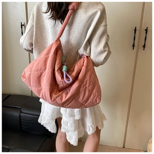 Detail of pink quilted tote bag with wide knotted shoulder strap and colorful rope charm