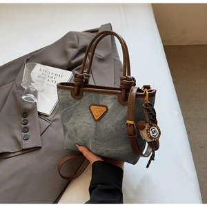 Detail of vintage retro bucket bag with brown leather handles and a round doll charm
