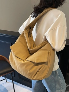Large mustard canvas tote bag with front utility pockets shown on model in a casual setting