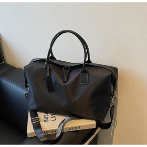 Detail of black nylon travel tote featuring dual handles and adjustable shoulder strap