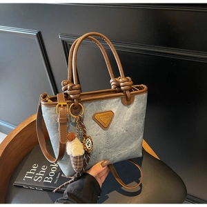 Detail of blue denim tote bag with brown leather handles and cute ice cream charm