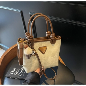 Close-up of retro canvas tote with leather trim, golden logo, and ice cream charm detail
