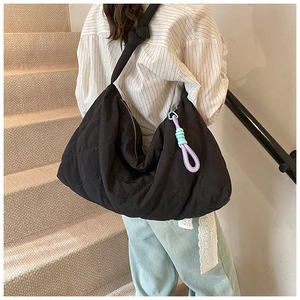 Detail of a large black quilted hobo bag with purple and mint green side tassels