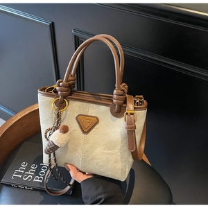 Detail of canvas bucket bag with brown leather trim and cute ice cream charm on a chair