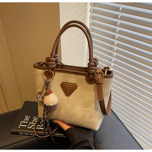 Close-up of contrast canvas bucket bag with leather trim and plush ice cream charm