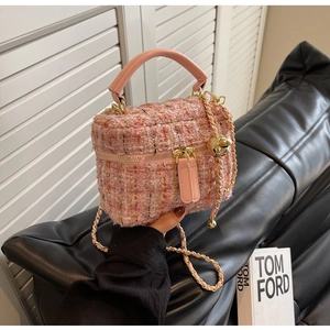 Detail of pink tweed chain bag with golden animal charm and leather top handle