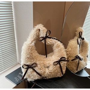 Detail of plush khaki hobo bag with brown leather bows on a vintage wooden shelf
