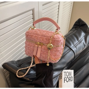 Close-up of pink tweed vanity bag with gold hardware and woven chain strap detail