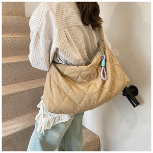 Close-up of khaki quilted tote bag with twisted rope detail on a shoulder strap
