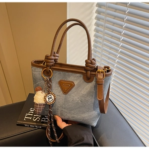 Detail shot of denim tote bag with brown leather trim and cute ice cream charm