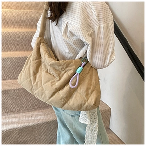 Detail of khaki quilted tote bag featuring purple braided ropes and white lace ribbon