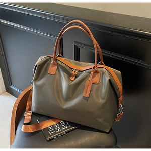 Detail of green nylon tote bag with brown leather handles and adjustable shoulder strap