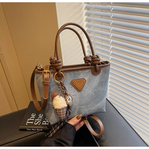Blue denim tote bag detail with brown leather trim, ice cream charm and knotted handle
