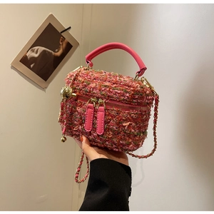 Close-up of pink tweed box bag featuring gold hardware and a detachable chain strap
