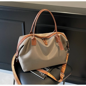 Detail of khaki nylon travel tote bag with brown leather handles on a vintage wooden chair