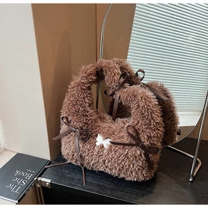 Detail of plush brown bag featuring white butterfly embroidery and leather ribbon ties