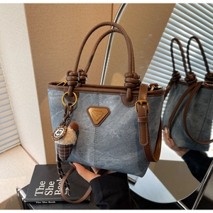 Detail of blue denim crossbody bag with brown leather trim and ice cream charm