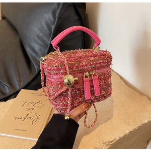 Macro detail of pink tweed texture and golden metal sphere accent on a chain bag