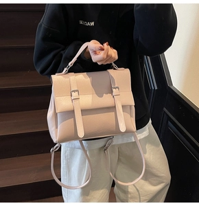 Dettaglio di uno zaino in pelle beige con fibbie decorative in argento e patta