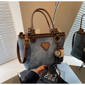 Detail of vintage blue denim texture tote bag with brown leather handles and brand logo