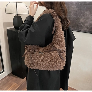 Detail view of coffee plush shoulder bag featuring faux fur texture and leather bow