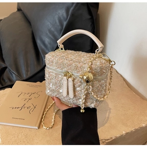 Detail of pink and beige tweed handbag with golden chain strap and ball pendant