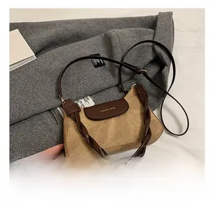 Close-up of khaki suede handbag with brown leather flap and woven handle detail