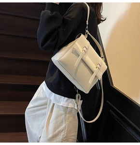 Detail of a vintage cream leather messenger bag with silver buckles and adjustable strap
