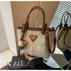 Detail view of canvas bucket bag with leather handles and plush ice cream charm
