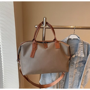 Detail of grey nylon travel tote featuring leather handles and adjustable shoulder strap