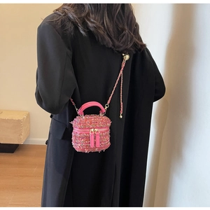 Pink tweed bucket bag detail showing leather chain strap and woven texture on model