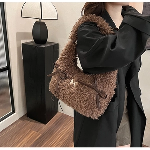 Detail of plush brown underarm bag with leather bows and gold metal horse charm buckle