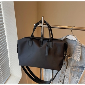 Close-up of black nylon tote bag with dual handles and adjustable shoulder strap