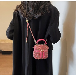 Detail of pink tweed chain bag showing woven texture and gold chain worn by a model