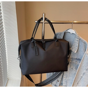 Large capacity black nylon travel tote bag shown hanging on a metal clothing rack.