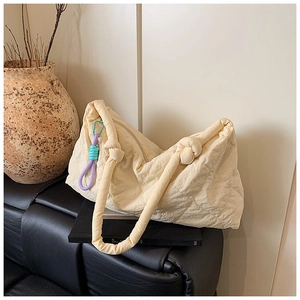 Close-up of cream quilted tote bag featuring a knotted handle and woven cord detail