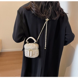 Detailed view of cream tweed mini box bag with gold chain strap on black coat