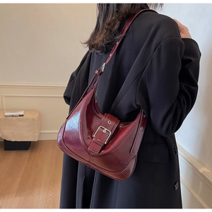 Details der burgunderfarbenen Hobo-Tasche mit großer Metallschnalle und Glanzleder