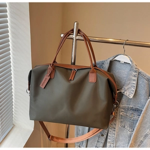 Detail of olive green nylon travel bag with brown leather trim and detachable shoulder strap