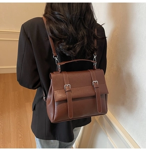 Dettaglio zaino vintage in pelle PU marrone con fibbie argento su un blazer nero