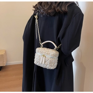 Detail of tweed bucket bag with metallic chain strap and gold woven texture