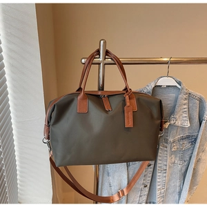 Detail of large nylon travel tote bag with leather handles shown on a metal hanger