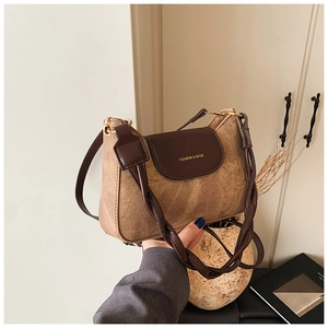 Detail of vintage brown suede square bag with braided strap and gold lettering