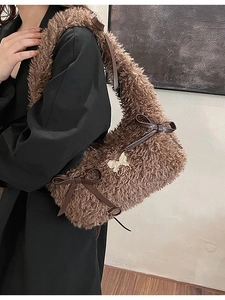 Brown fuzzy faux fur shoulder bag with satin bows and golden butterfly logo on a model
