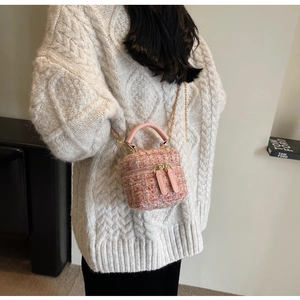 Detailed shot of pink tweed mini crossbody bag with gold chain strap and dual zippers