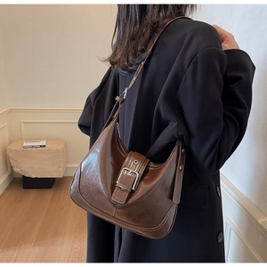 Braune Hobo-Tasche aus Leder mit Silberschnalle über einem schwarzen Blazer getragen