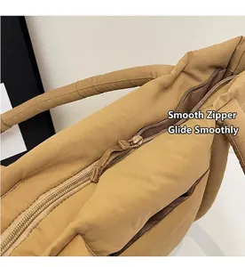 Détail de la fermeture éclair et du tissu matelassé kaki sur un sac fourre-tout