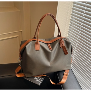 Detailed view of the dark green nylon travel tote bag with leather handles and orange strap